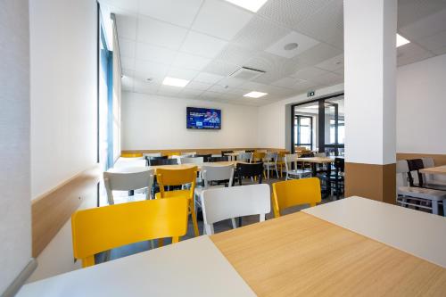 an empty classroom with tables and yellow chairs at B&B HOTEL Les Herbiers in Les Herbiers