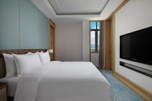a bedroom with a large white bed and a flat screen tv at C&D Hotel,Xiamen Xiang'an-Late Check Out & Free Welcome Snacks in Xiamen