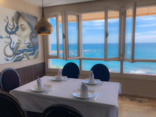 a dining room with a table with a view of the ocean at Hotel Patricia in Torreguadiaro