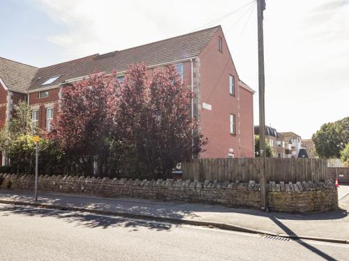 a brick house with a fence and a tree at Swanage Town Apartment in Swanage