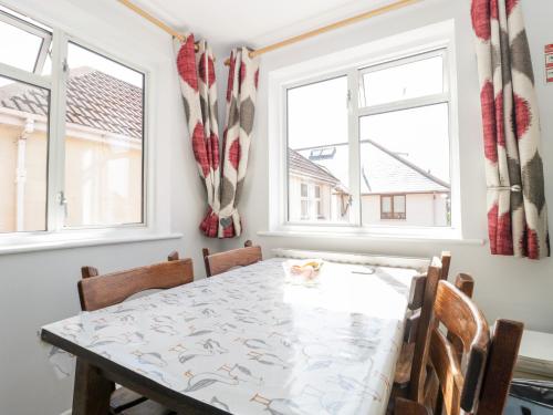 a dining room with a table and two windows at Swanage Town Apartment in Swanage