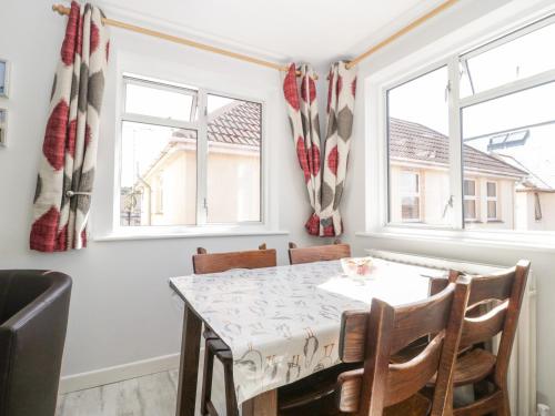 a dining room with a table and chairs and windows at Swanage Town Apartment in Swanage