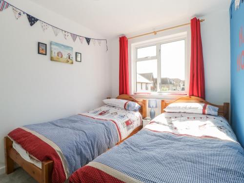 two beds in a room with a window at Swanage Town Apartment in Swanage