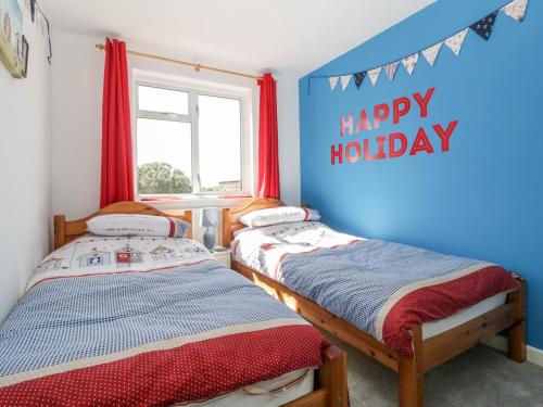 two beds in a room with a happy holidays sign at Swanage Town Apartment in Swanage