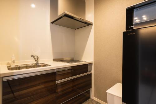 a small kitchen with a sink and a refrigerator at GRAND BASE Nagasaki Chukagai in Nagasaki