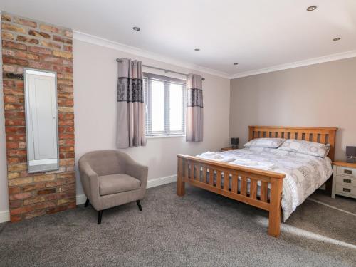 a bedroom with a bed and a chair and a brick wall at The Stables in Boston
