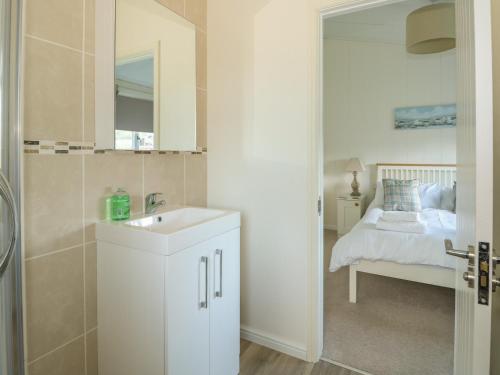 a white bathroom with a sink and a bed at Pentney Lodge in Kings Lynn