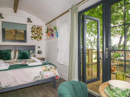 a bedroom with a bed and a balcony at High Rigg Shepherd's Hideaway in Brampton