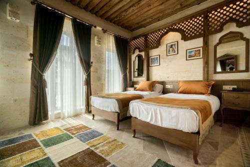 a bedroom with two beds and a large window at Sobek Stone House Cappadocia in Nevsehir
