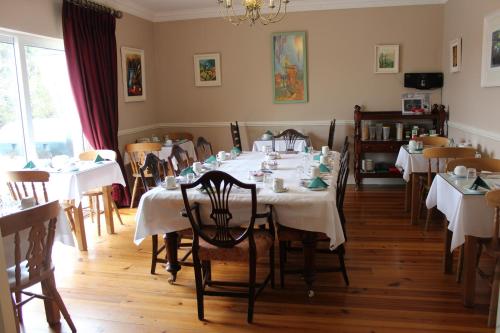 uma sala de jantar com mesas e cadeiras brancas e um lustre em Adare Country House em Adare