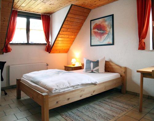 
a bedroom with a bed, a desk and a lamp at Pension La Cascina in Tuttlingen

