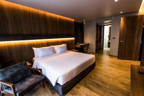 a bedroom with a large bed and a chair at The Teak Hotel in Mae Sot