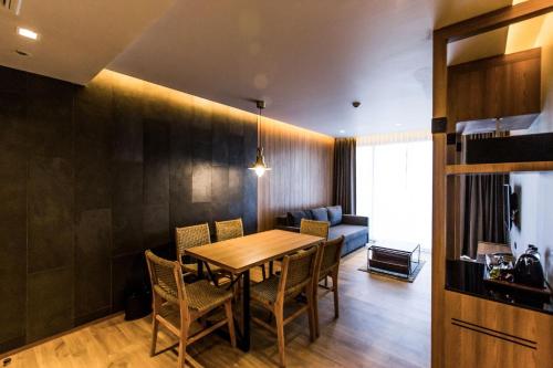 a dining room with a table and chairs and a couch at The Teak Hotel in Mae Sot