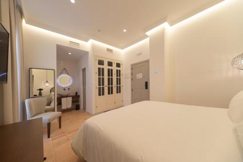 a white bedroom with a bed and a desk and a chair at Albariza Hotel Boutique in Sanlúcar de Barrameda