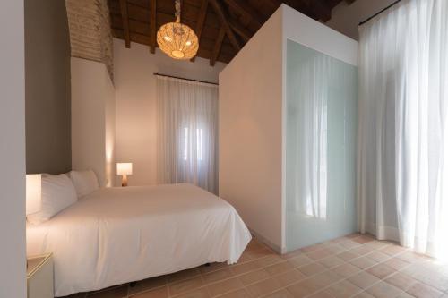 a bedroom with a white bed and a chandelier at Albariza Hotel Boutique in Sanlúcar de Barrameda