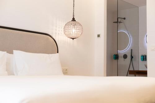 a bedroom with a white bed and a chandelier at Albariza Hotel Boutique in Sanlúcar de Barrameda