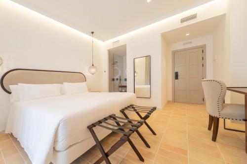 a bedroom with a white bed and a table and chairs at Albariza Hotel Boutique in Sanlúcar de Barrameda