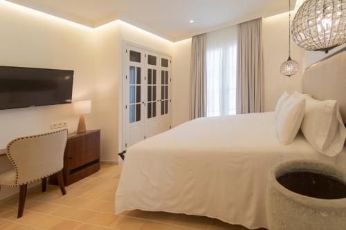 a bedroom with a large white bed and a tv at Albariza Hotel Boutique in Sanlúcar de Barrameda