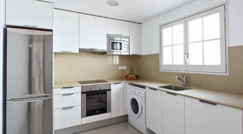uma cozinha branca com um frigorífico e uma máquina de lavar louça em Villa Reymar - diseño y vistas al mar em Tossa de Mar