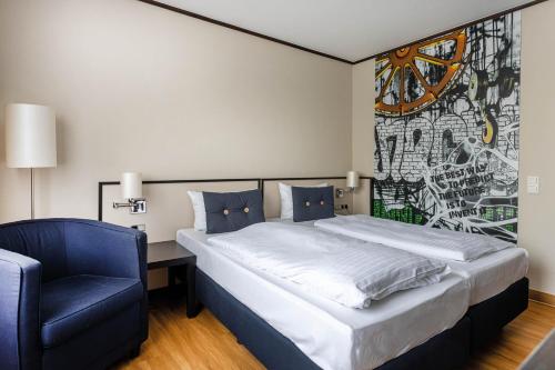 a bedroom with a large bed and a blue chair at Seminaris Hotel Bad Honnef in Bad Honnef am Rhein