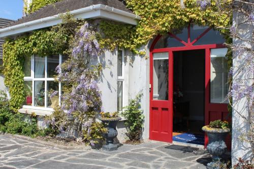 a red door leading to a house with a garden at Adare Country House in Adare
