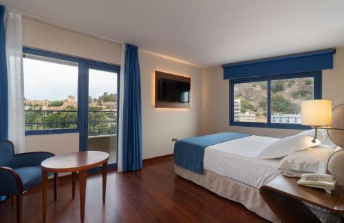 a hotel room with a bed and a desk and window at Hotel MS Maestranza Málaga Centro in Málaga