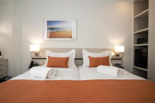 a bedroom with a large bed with orange and white pillows at Best Western Plus Larco Hotel in Larnaka