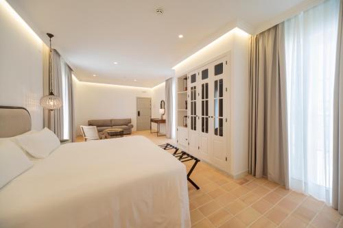 a bedroom with a white bed and a living room at Albariza Hotel Boutique in Sanlúcar de Barrameda