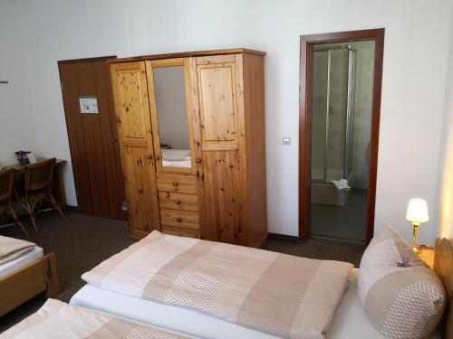 a bedroom with a bed and a wooden cabinet at Pension am Heusteig in Stuttgart