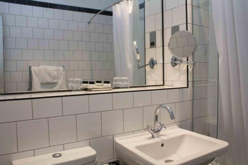 a white bathroom with a sink and a mirror at Peebles Hydro in Peebles
