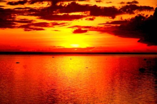 a sunset over a body of water with boats at Tambua Sands Beach Resort in Korotogo