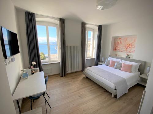 a bedroom with a bed and a desk and two windows at Five Flowers Guest House in Trieste