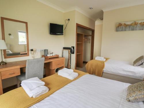 a hotel room with two beds and a desk and a mirror at Llety Ceiro Guesthouse in Aberystwyth