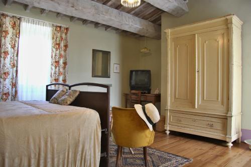 een slaapkamer met een bed, een stoel en een televisie bij Poggio Dei Prugnoli in Tavoleto