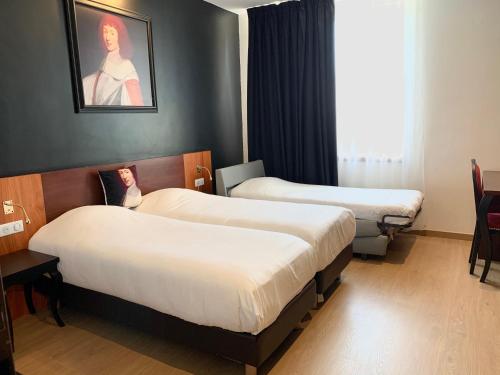 a hotel room with two beds and a window at Hotel des Lys in Versailles