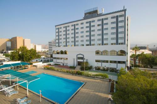 un grande edificio con una piscina di fronte a un edificio di Hotel Muscat Holiday a Mascate