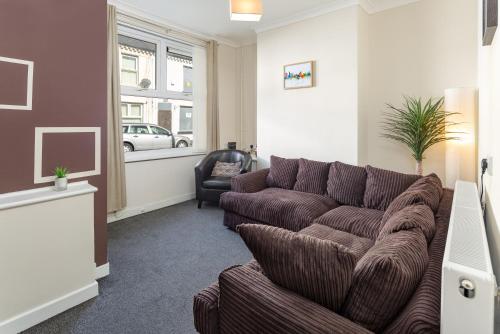 a living room with a brown couch and a window at Cosy Anfield Guesthouse - Close to Stadium & City in Liverpool