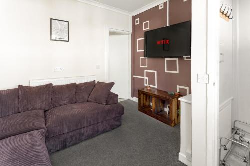 a living room with a couch and a flat screen tv at Cosy Anfield Guesthouse - Close to Stadium & City in Liverpool