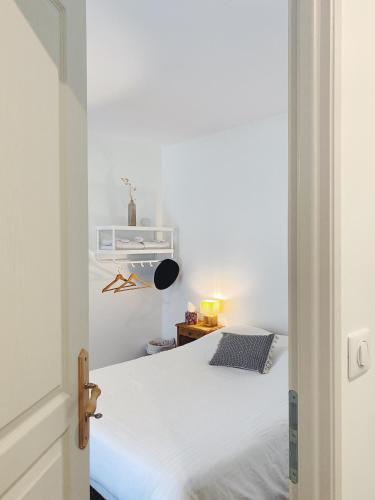 une chambre avec un lit blanc dans une pièce dans l'établissement L'anne xe, studio indépendant, à Valeuil