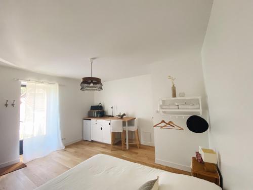 um quarto branco com uma cama e uma cozinha em L'anne xe, studio indépendant em Valeuil