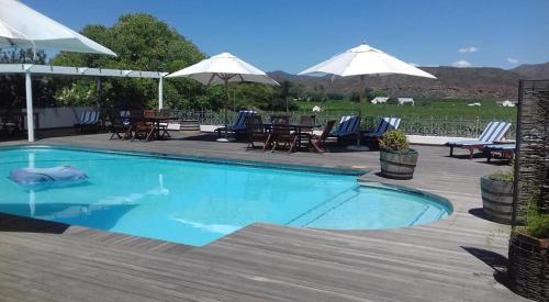 a swimming pool with chairs and tables and umbrellas at Excelsior Manor Guesthouse in Ashton