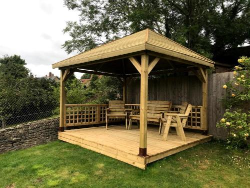 a wooden gazebo with chairs and a table at Mallows Byre Yetminster in Sherborne