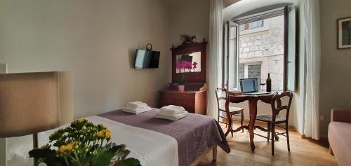 a bedroom with a bed and a desk with a laptop at Muziqa Apartments in Dubrovnik