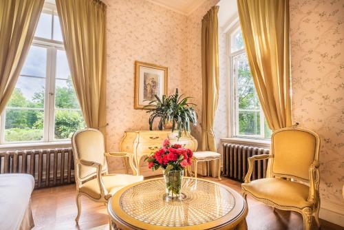 a living room with a table with a vase of flowers at Liepupe Manor in Liepupe