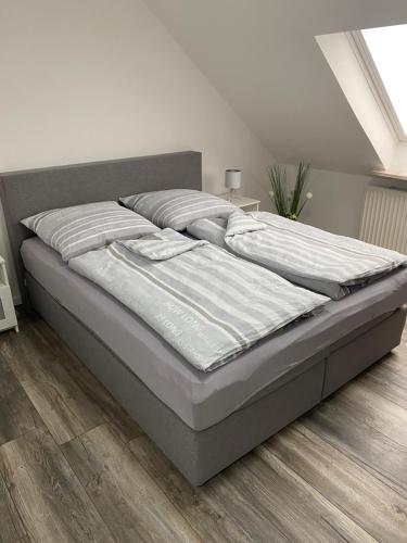 uma cama num quarto branco com piso em madeira em Apartments Benzweg 2 em Northeim