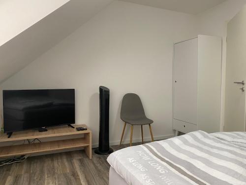 a bedroom with a flat screen tv and a chair at Apartments Benzweg 2 in Northeim