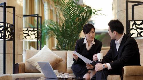 two women and a man sitting on a couch with a laptop at Crowne Plaza Yantai Sea View by IHG in Yantai