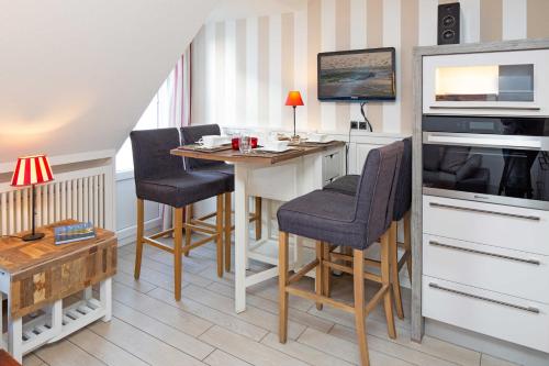una piccola cucina con tavolo, sedie e televisore di Carlotta s Beachroom a List