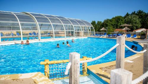 una gran piscina con gente en el agua en Mobil Home XXL 4 chambres - Camping Le Domaine de Beaulieu, en Givrand