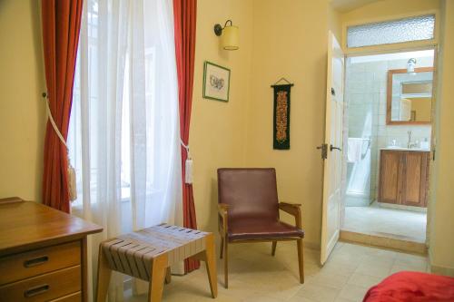 a room with a chair and a bathroom with a sink at The Templer Inn in Jerusalem